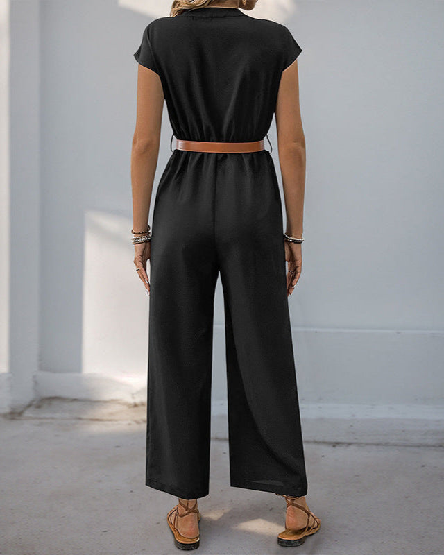 Back view of a woman in a black jumpsuit, showcasing its relaxed fit and cinched waist with a tan belt.