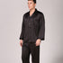 Front view of model in solid black silk pajamas with notched collar and long sleeves against neutral backdrop