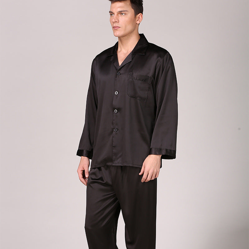 Front view of model in solid black silk pajamas with notched collar and long sleeves against neutral backdrop