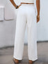 Back view of white wide-leg linen pants with an elastic waistband, worn with a white crop top and flat sandals.