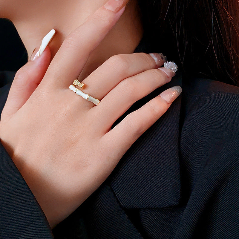Gold and white bamboo joint ring worn with neutral nails