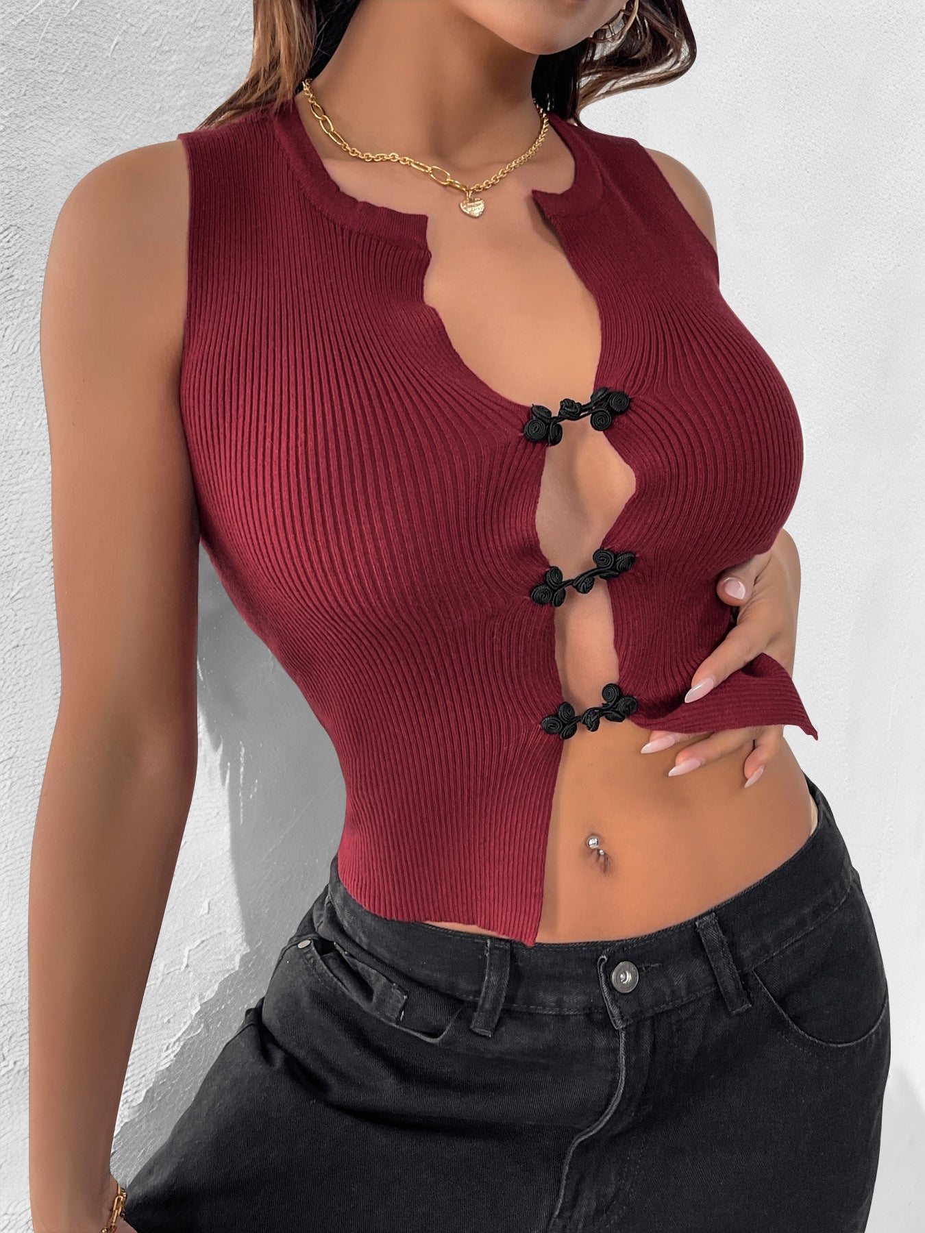 Close-up of a woman in a burgundy sleeveless top with black knotted fasteners, highlighting the ribbed fabric.