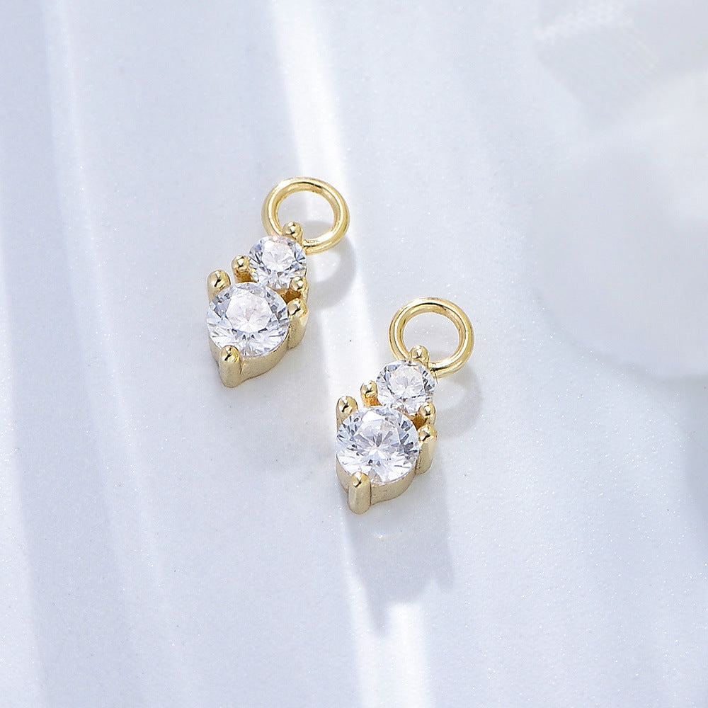 Gold diamond drop charms with double crystal stones in prong settings, displayed on white background with soft shadows