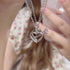 Heart and arrow pendant necklace worn with floral print dress, focused on silver pendant detail
