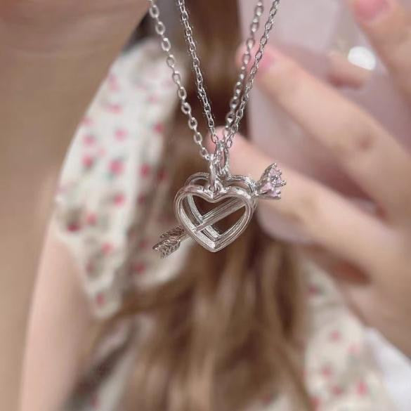 Heart and arrow pendant necklace worn with floral print dress, focused on silver pendant detail