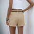 Back view of beige high-waisted shorts with black lace trim and an elastic waistband, styled with a white crop top.