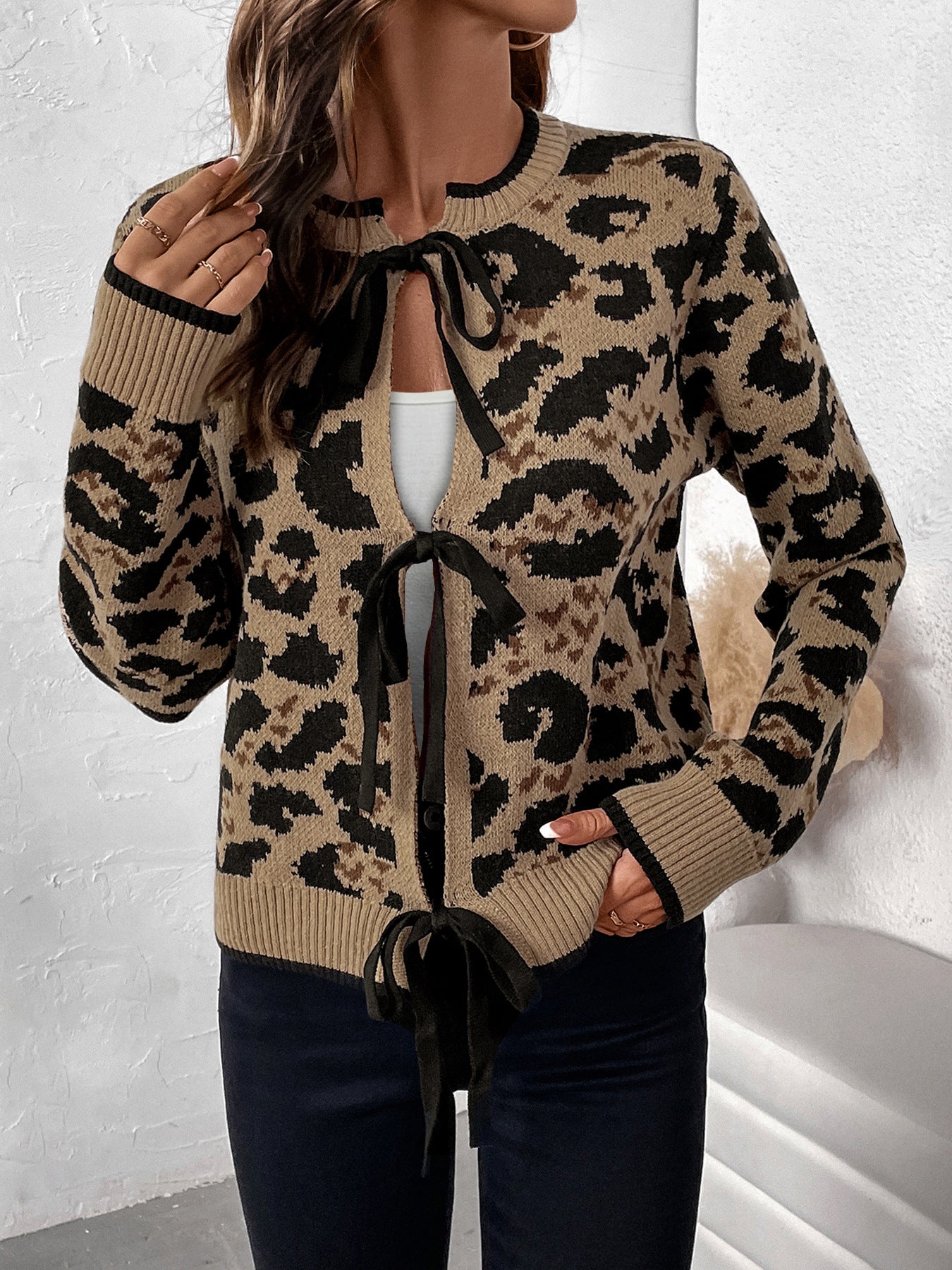 Close-up view of model in tan leopard cardigan with black trim, showing tie closure detail