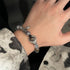 Bracelet styled on wrist showing crystal beads and silver charms against tie-dye fabric