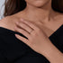 Dainty gold stackable ring with multicolored stones worn on hand against black top, showing everyday styling