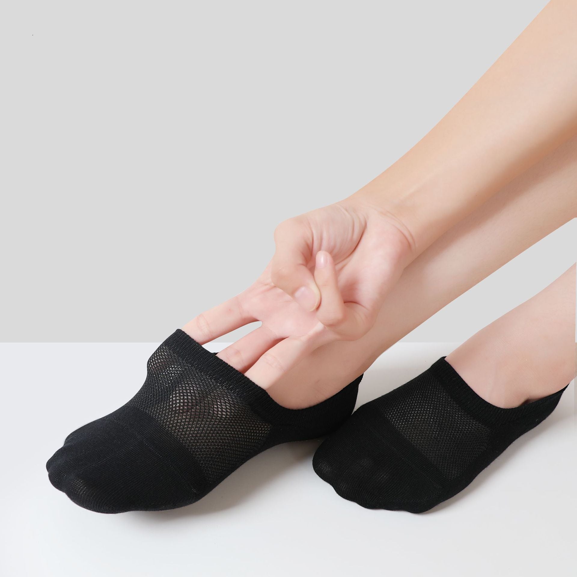 Black no-show socks being worn, displaying mesh ventilation panels and low-cut silhouette