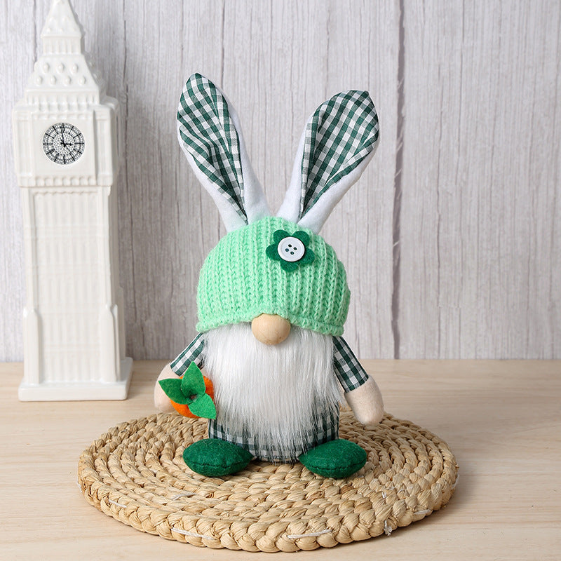 Green bunny gnome plush with a knit hat and carrot decoration, sitting on a woven mat with a neutral background.