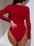 Back view of a woman in a red ribbed long-sleeve bodysuit, showing a sleek fit and full coverage, accessorized with silver rings and manicured nails.