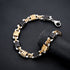  A detailed shot of the black and gold stainless steel bracelet on a black textured surface, showcasing the intricate link pattern and secure clasp.