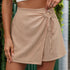 Close-up of beige mini skort featuring ruched circular tie detail and wrap-style front, casual summer fashion design