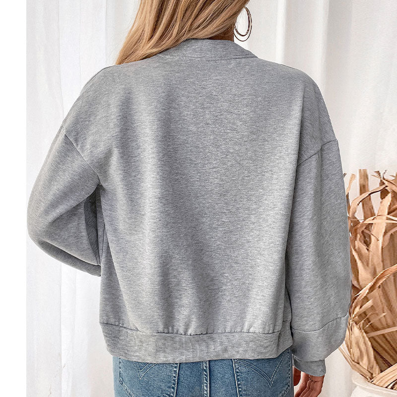 Back view of gray bomber jacket with white crop top and blue jeans