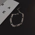 Silver Figaro chain bracelet on minimalist black and white background