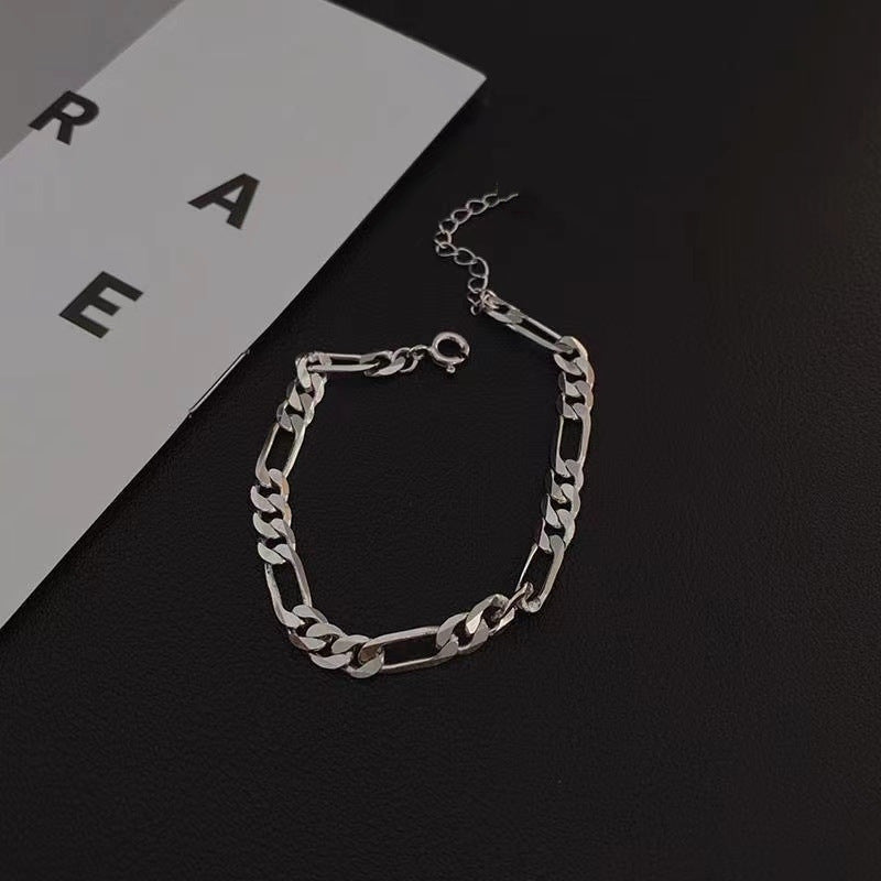 Silver Figaro chain bracelet on minimalist black and white background