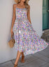 A woman twirls in a flowy floral midi dress with a drawstring waist and tiered skirt, wearing a straw hat and brown sandals.