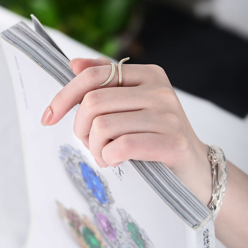 Hand wearing wave ring while holding book, showing crystals against white sleeve