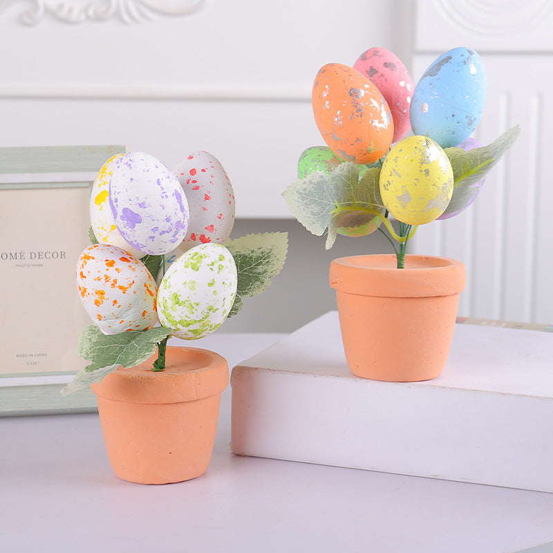 Easter egg tree in a terracotta pot with pastel speckled eggs and green leaves, displayed on a white surface with decor.