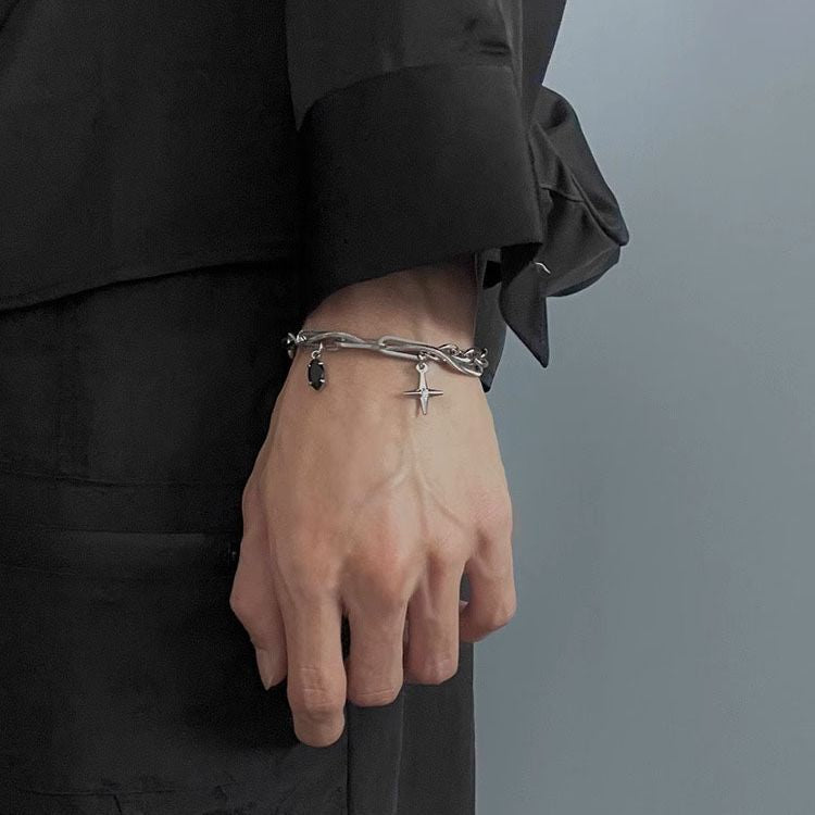 Stainless steel charm bracelet with cross and gemstone details, worn on a wrist against a neutral background for a modern aesthetic.