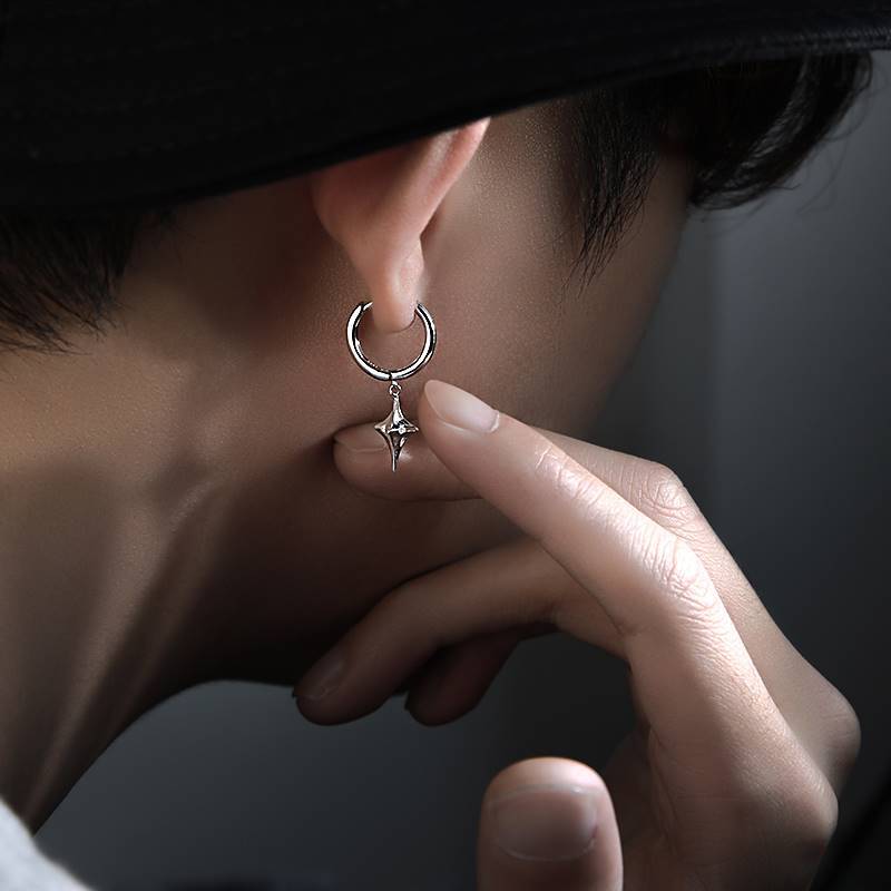 Silver star drop hoop earring being held on ear, artistic side profile shot