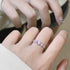 A person viewing silver heart ring with pink center stone and crystal accents in mirror reflection, wearing white ribbed sleeve