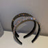 Two rhinestone-covered headbands, one black and one iridescent, displayed on a white surface with a subtle sparkle effect.