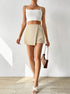 Full-length summer outfit with cream wrap skort, white crop top, cross-strap sandals and brown chain shoulder bag