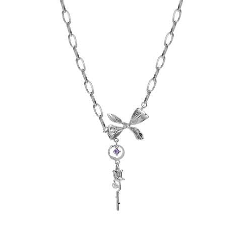 Close-up of silver necklace with central bow charm, purple gemstone in circular setting, and decorative key pendant