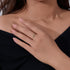 Close-up of a hand wearing delicate gold eye-shaped ring with blue sapphire against black clothing