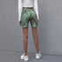 Model faces away, showing the rear fit of green ribbed tie-dye biker shorts paired with a white cropped top and sneakers