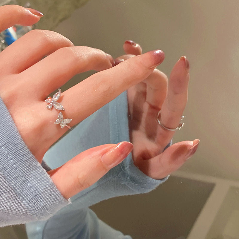 Close-up of a silver butterfly ring with crystal details, reflected in a mirror