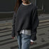 Side view of charcoal grey ribbed sweater layered over white t-shirt, paired with light denim jeans