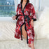 Red satin robe with heart and "love" print, black trim, woman holding wine glass in urban setting