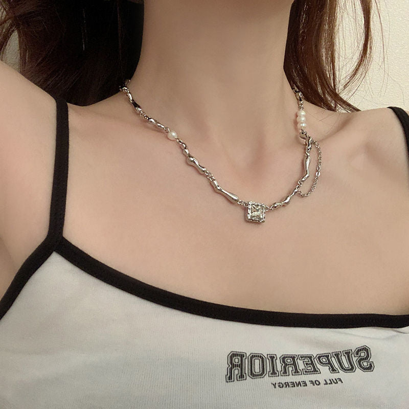 Silver pearl-accented branch-link necklace with a gemstone pendant worn on a woman’s neck