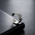 A silver adjustable ring with a hammered texture resting on a black leather surface, reflecting light.