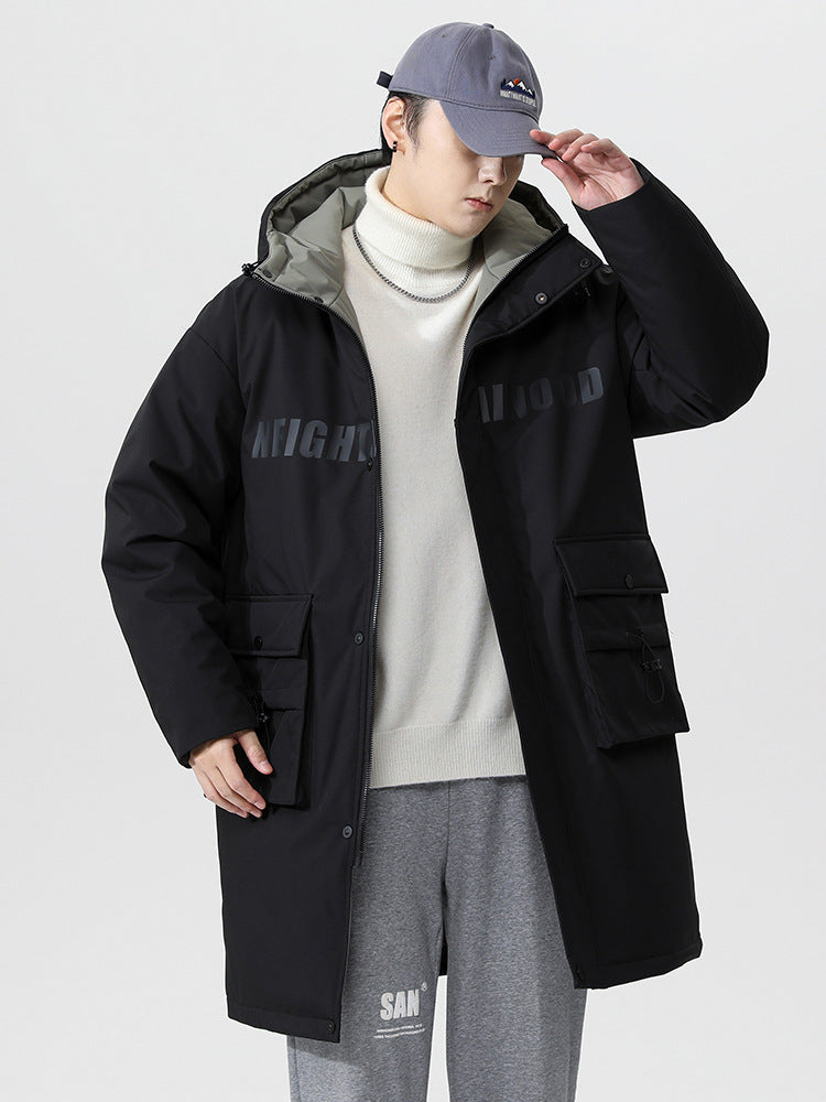 A man adjusting his gray cap while wearing black NEIGHBORHOOD parka with white turtleneck and gray sweatpants against white background