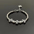 Stainless steel bracelet with silver beads, floral cross charms, and pearl accents for a vintage aesthetic.