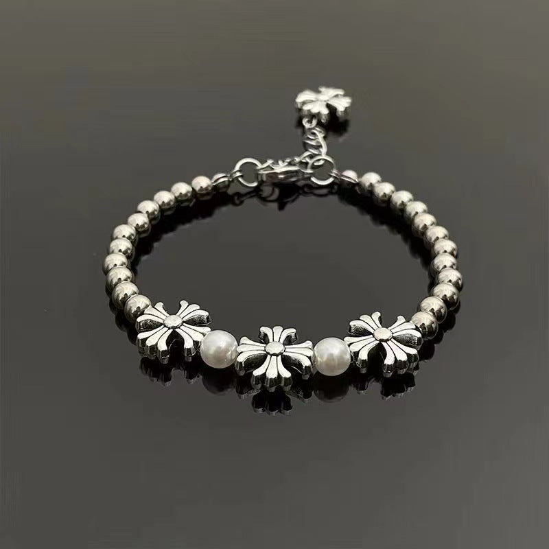 Stainless steel bracelet with silver beads, floral cross charms, and pearl accents for a vintage aesthetic.