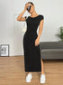 A woman in black fitted maxi dress with cap sleeves and side slit, holding drink and accessorized with white bag