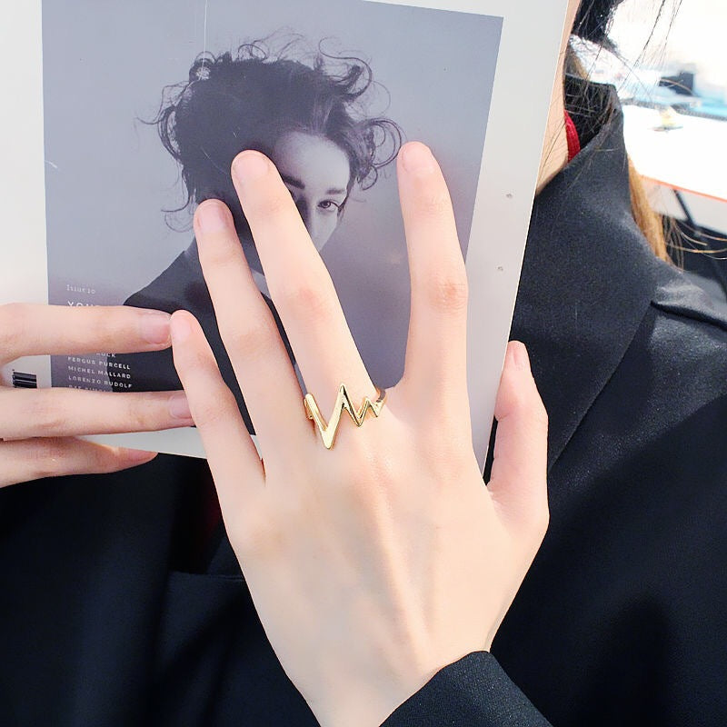 Gold lightning bolt ring shown on hand holding a black and white portrait photo