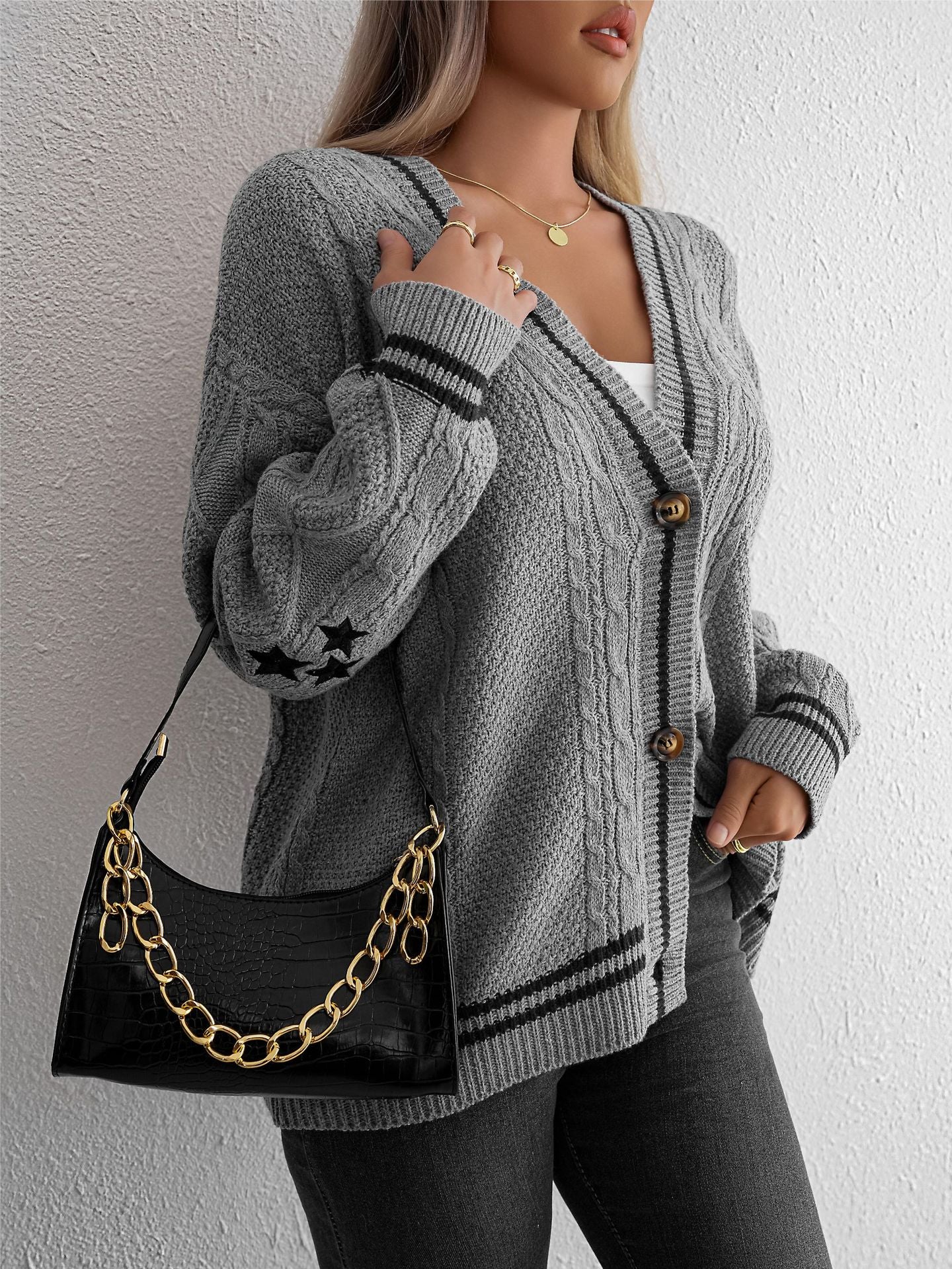 Gray cable knit cardigan with star details and black trim, accessorized with black croc-effect handbag