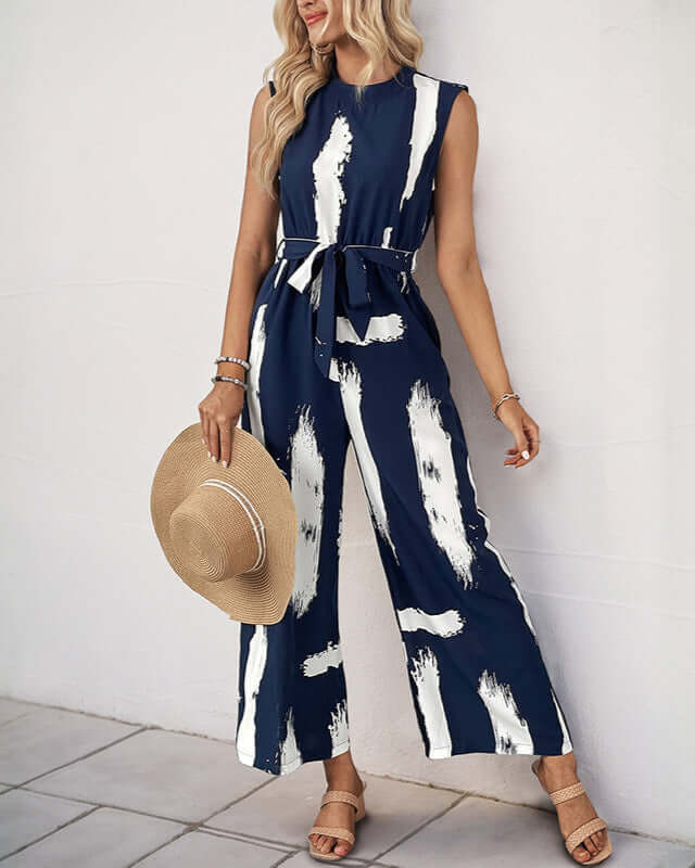 Side view of a navy sleeveless jumpsuit with a belted waist and relaxed fit, featuring white brushstroke detailing