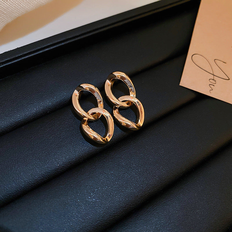 Interconnected gold chain link earrings on black background