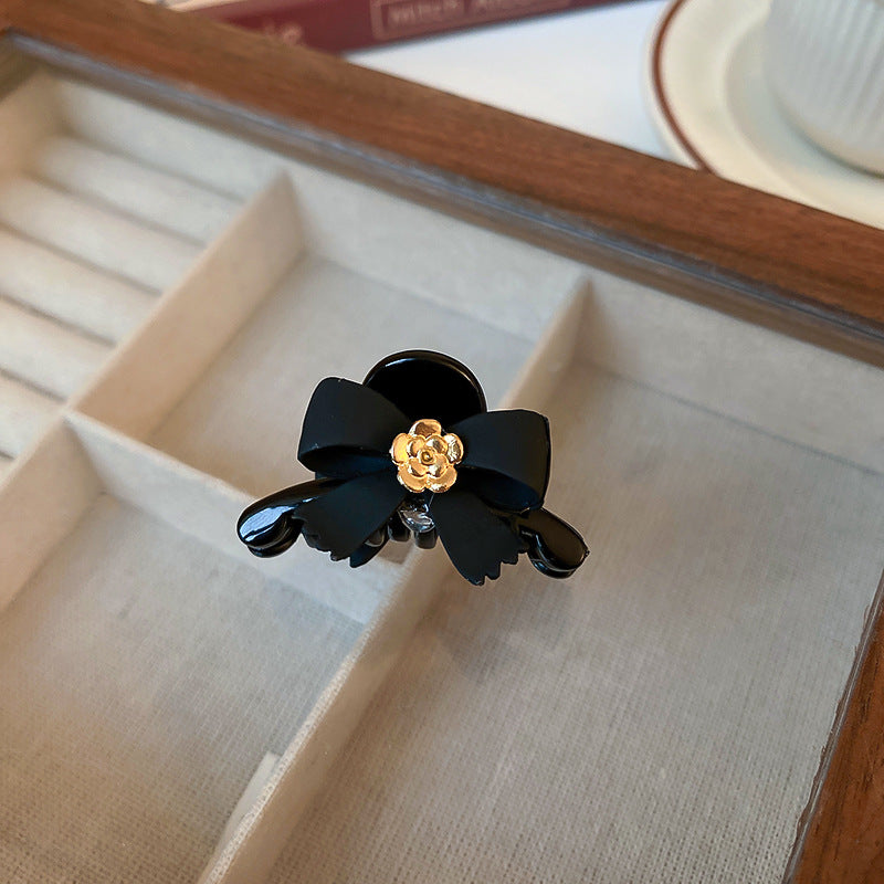 Close-up of black bow hair clip with golden rose detail