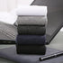 Flat lay of five pairs of socks in black, gray, navy, and white on a textured surface