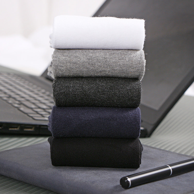 Flat lay of five pairs of socks in black, gray, navy, and white on a textured surface