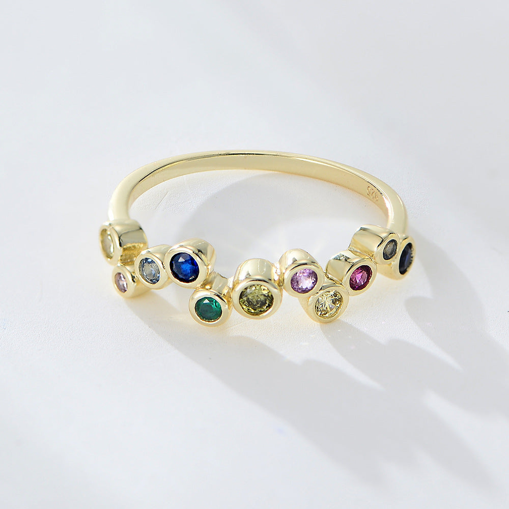 A woman wearing 925 stamped gold rainbow bubble ring with bezel-set gemstones photographed on white surface