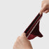 Hands stretching burgundy fluffy sock to demonstrate material elasticity, white stripes visible